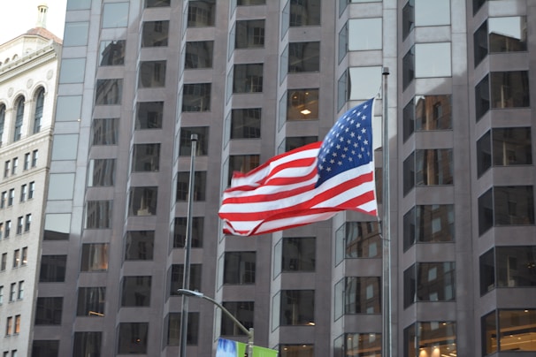 Modern corporate office building with American flag waving outside on a sunny day.