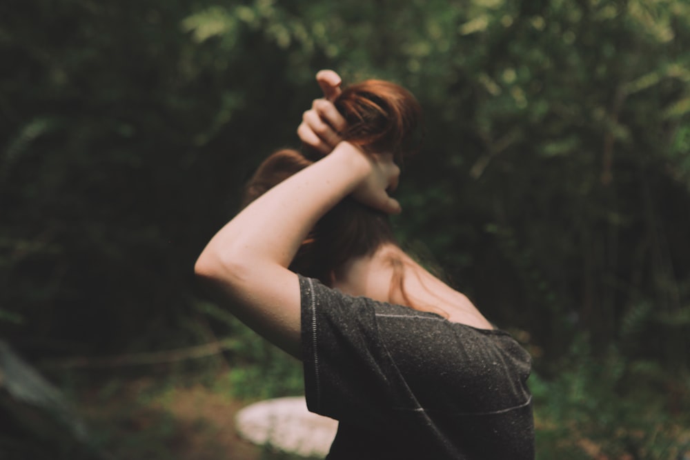 woman wearing black shirt tying up hair