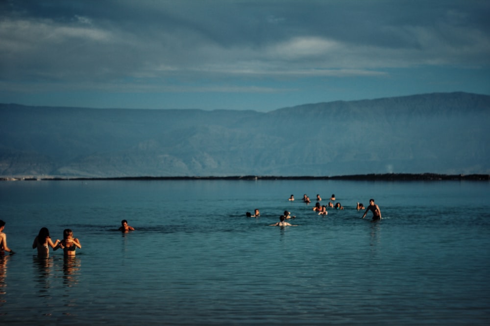 group of people in body of water near green mountain