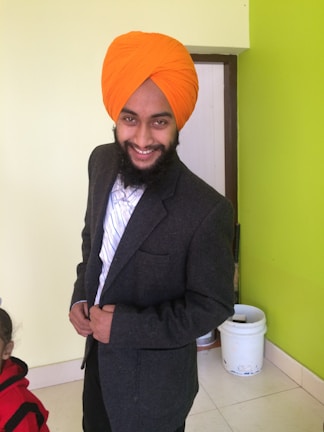 Smiling Indian man in business casual clothing standing in a modern office space.