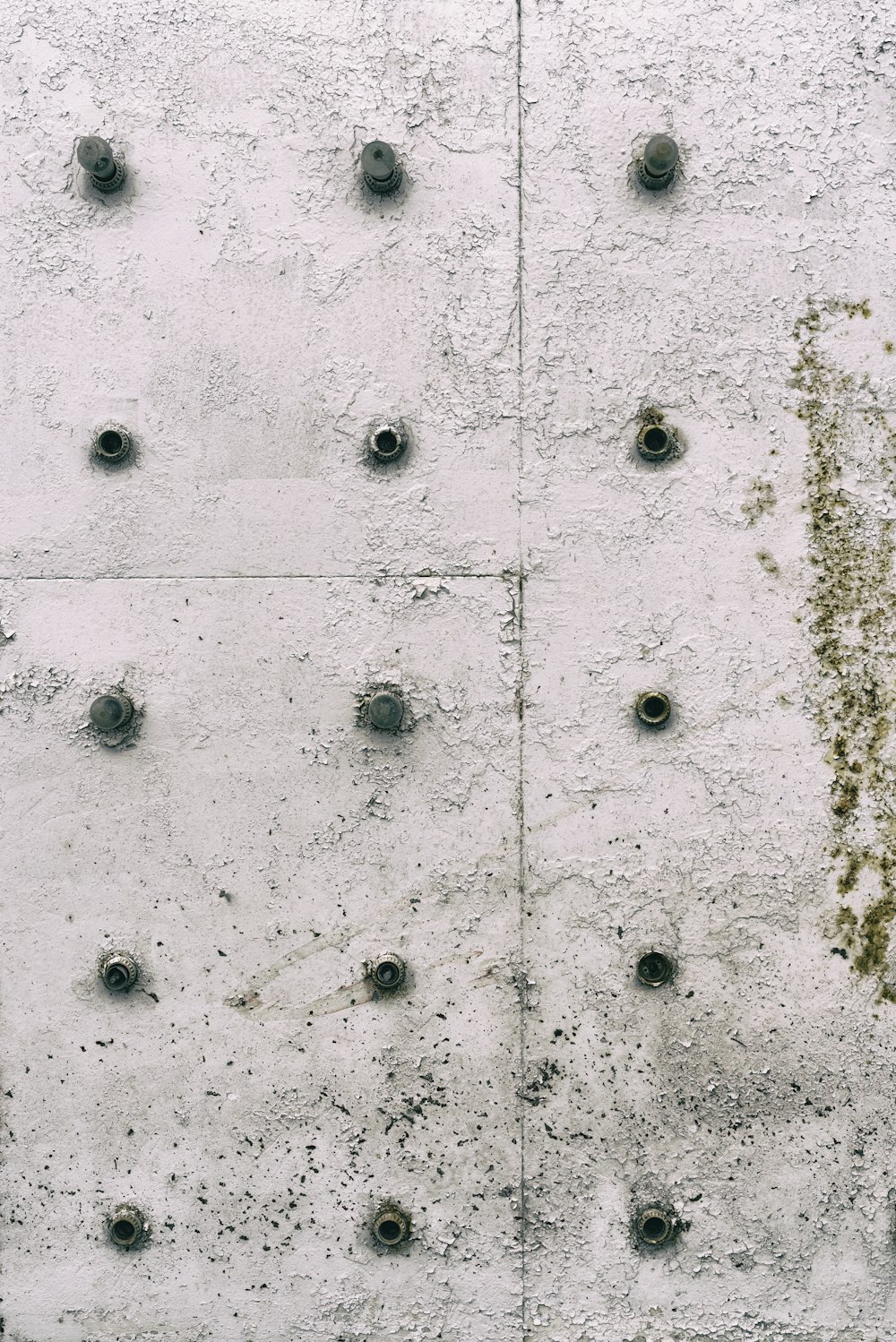 a concrete wall with rivets and holes on it