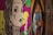 A stylized, graphic illustration of a person with exaggerated features, including large eyes and decorative tattoos. There is smoke rising from the corner of the mouth. The background features vibrant colors like pink and yellow, with abstract patterns and designs.