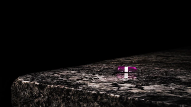 Close-up of the three Aura pills: blue, pink, and obsidian, elegantly arranged on a sleek white surface.