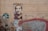 A wall with urban graffiti and street art. There is a detailed portrait of a man painted on a rectangular section of the wall. To the left, a street sign reads 'Strada Arthur Verona'. Surrounding the portrait are various graffiti tags and colorful patterns. The overall aesthetic is gritty and artistic.