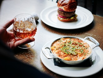 person holding clear snifter beside bowl of soup