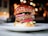 Close-up of a gourmet burger with fresh toppings on a wooden table.