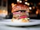 Close-up of a gourmet burger with fresh toppings on a wooden table.