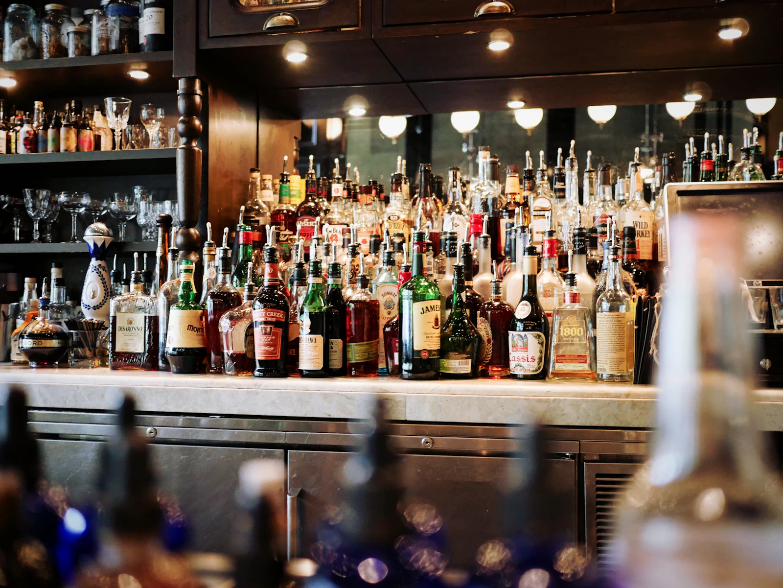 Back bar cabinet lined with liquor bottles, the inventory a bar manager counts each week