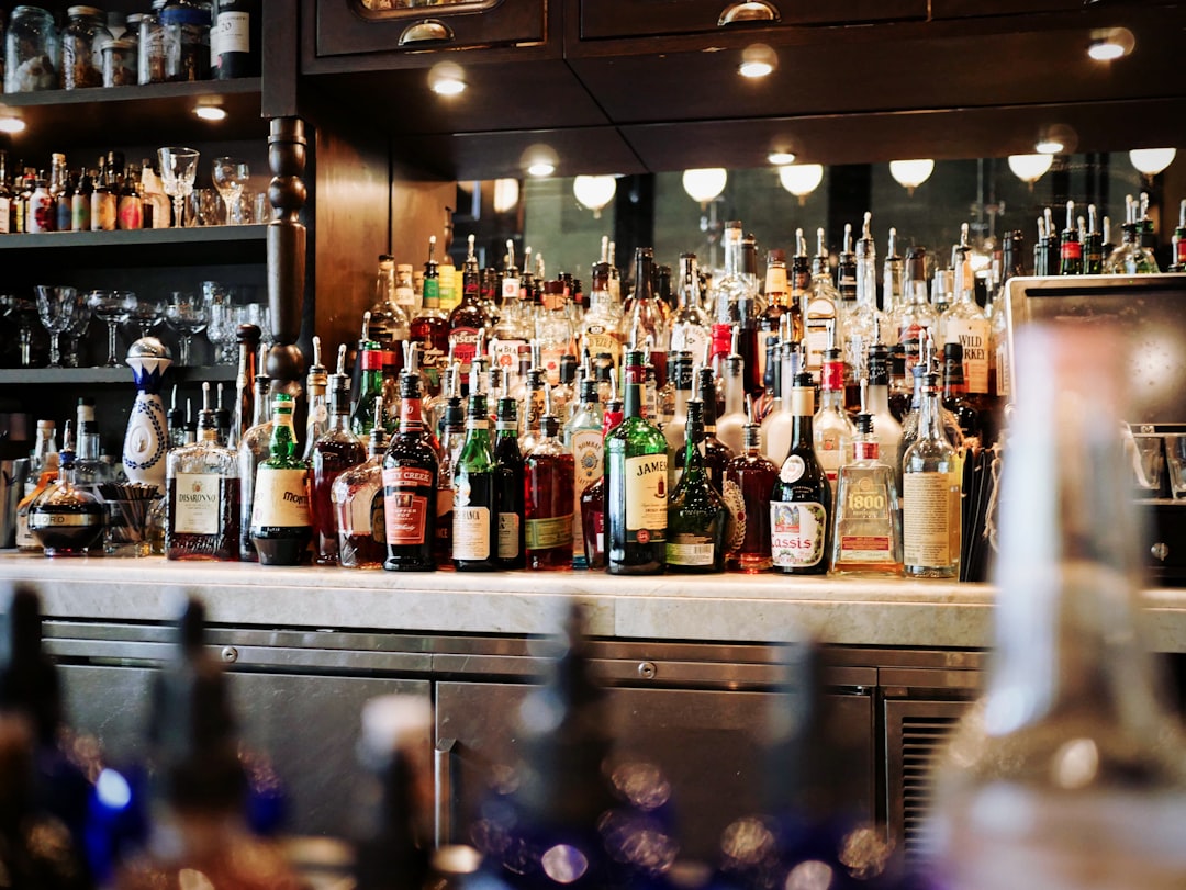 liquor bottles on white and brown wooden cabinet, Busy bar shelf