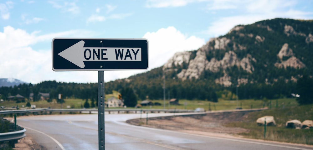 One Way street sign beside road far at the mountain during daytime