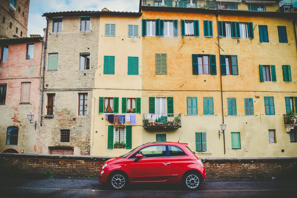 red 3-door hatchback parked near the building