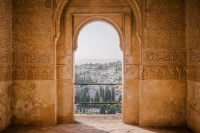 An arched stone doorway framing a view of the white buildings in Granada