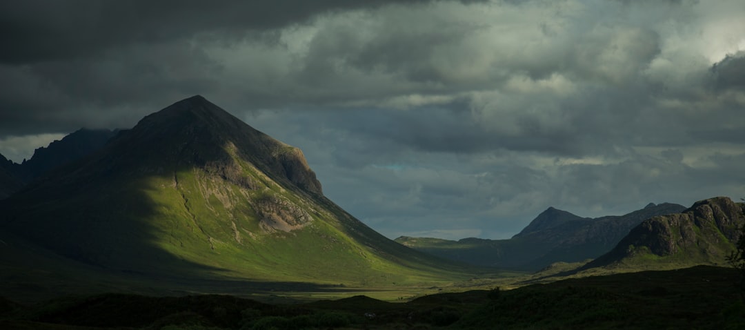 landscape photography of grass covered mountains under gray sky