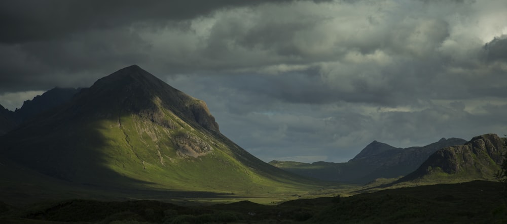 landscape photography of grass covered mountains under gray sky