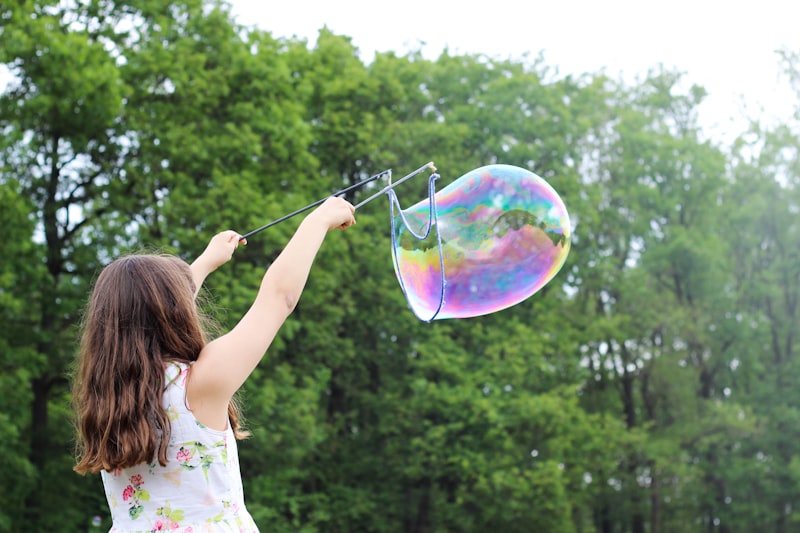 Niña jugando con burbujas de luz al sol
