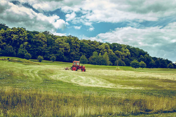 Trator agrícola vermelho em campo verde