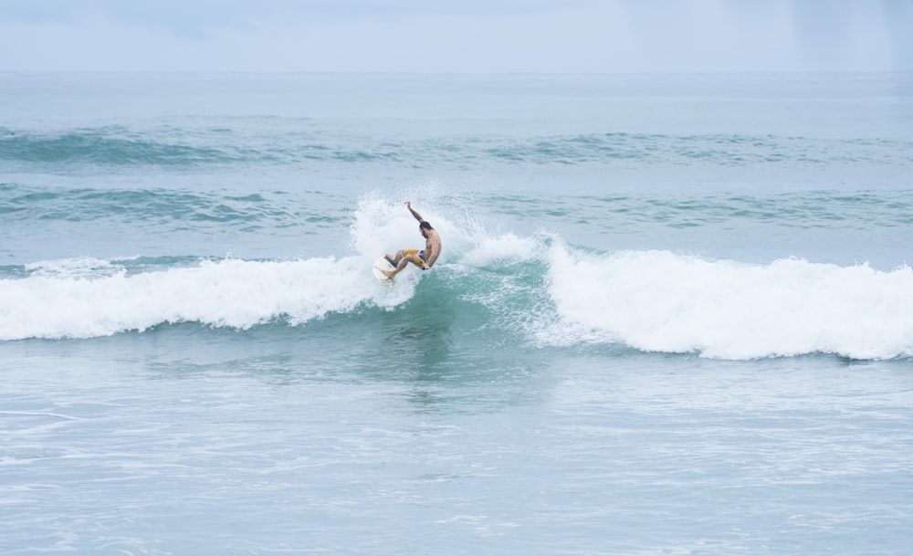 man riding a surfboard facing the waves on the ocean