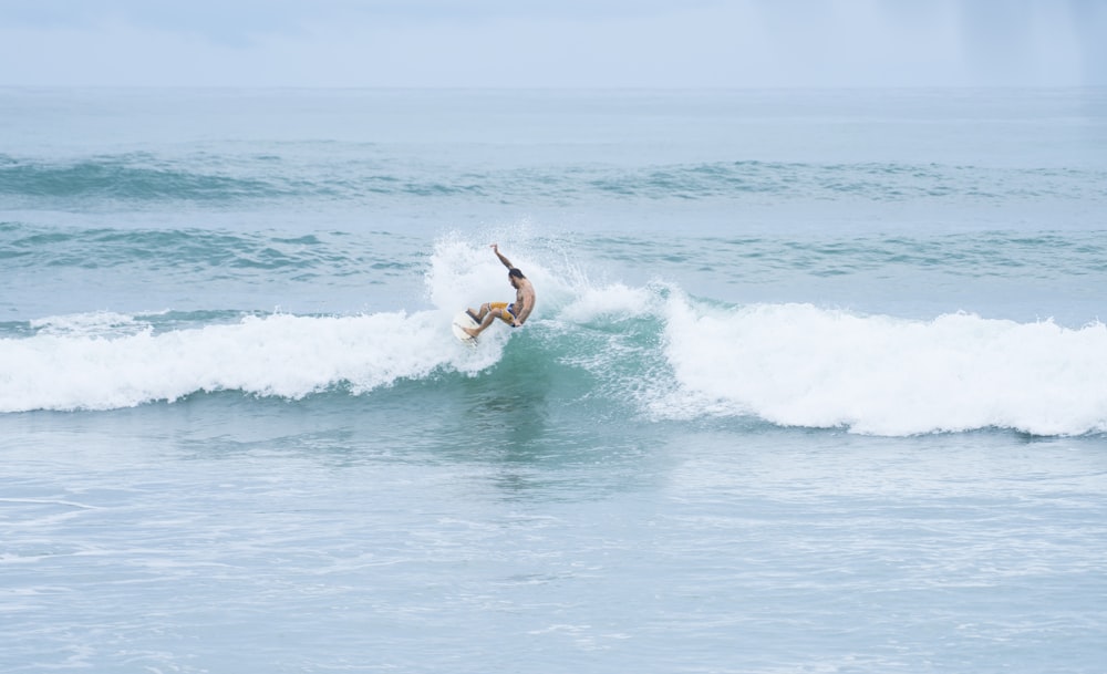 uomo che cavalca una tavola da surf di fronte alle onde sull'oceano