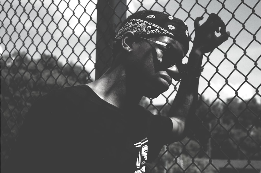 grayscale photo of person holding cyclone fence