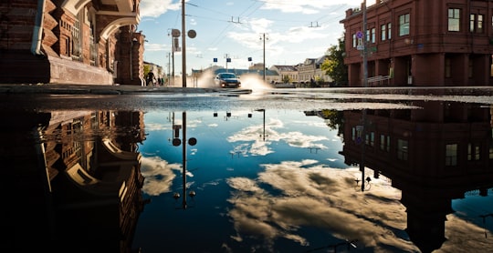 blue and white sky reflecting on water between brown buildings during daytime in Vladimir Russia