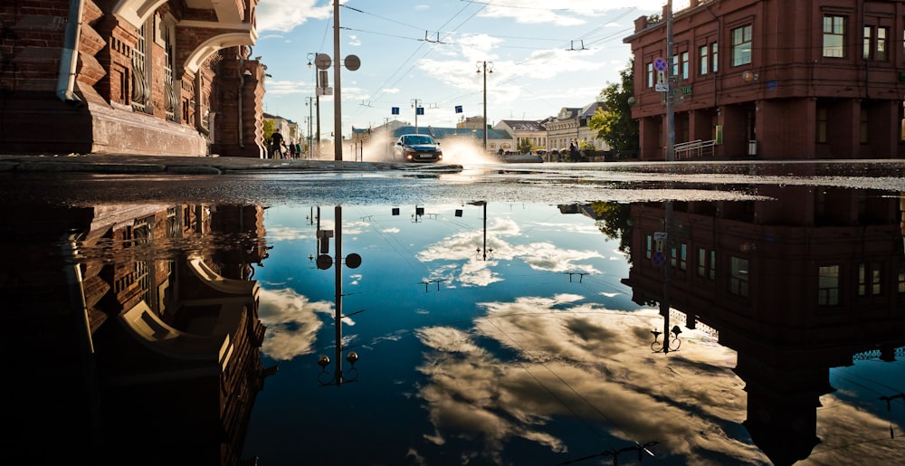 blue and white sky reflecting on water between brown buildings during daytime