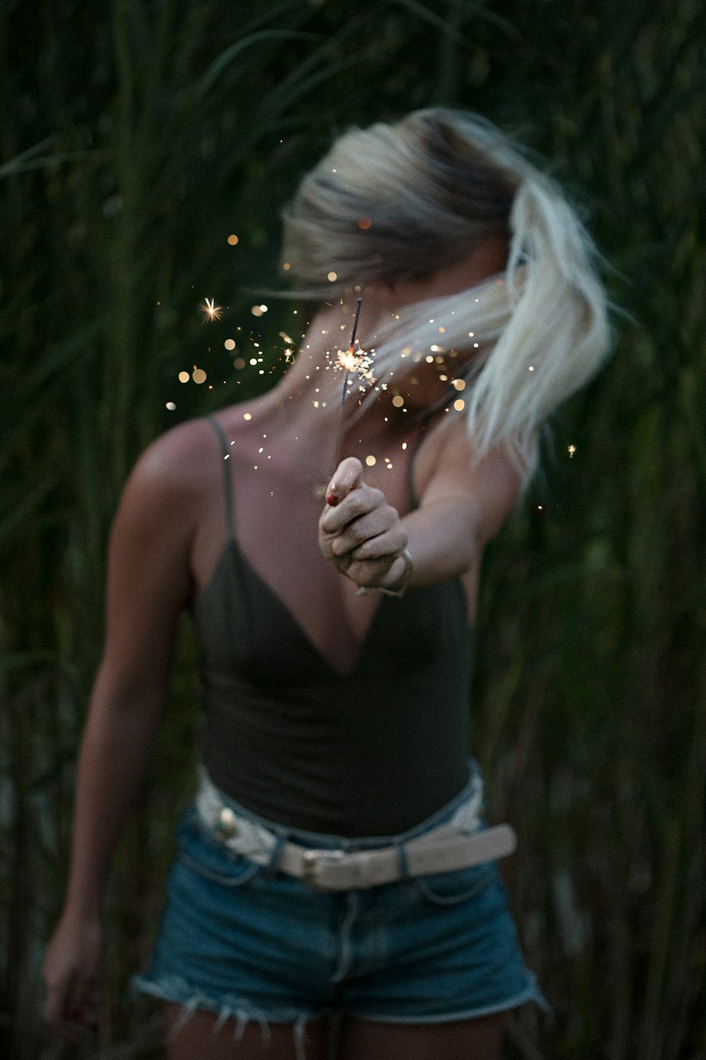 selective focus photo of woman holding sparkler while looking away