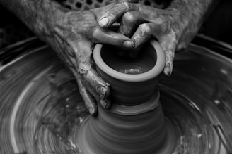 Messy hands sculpting on a pottery wheel in motion