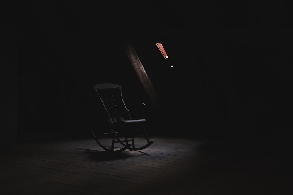 sedia a dondolo in legno marrone all'interno della stanza buia