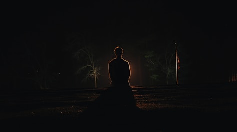 A peaceful figure practicing yoga under a starry night sky.