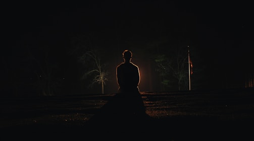 A serene figure meditating under a starry night sky.