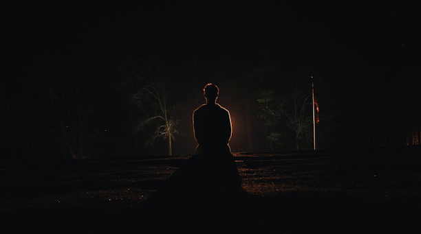 A peaceful scene of a person meditating outdoors under a starry night sky.