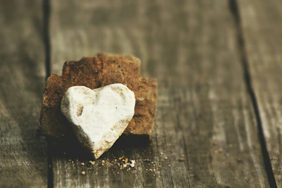 A polished rose quartz heart resting on a wooden table with gentle sunlight.