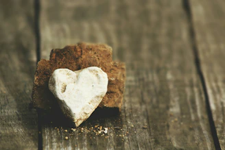 A polished rose quartz heart resting on a wooden table with gentle sunlight.