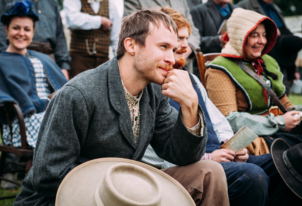 man wearing black coat sitting beside man in blue vest during daytime