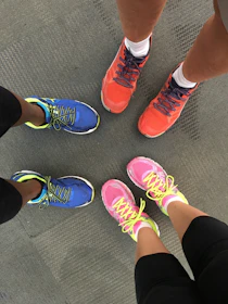 A group of runners laughing and stretching together in colorful outfits before a morning session.