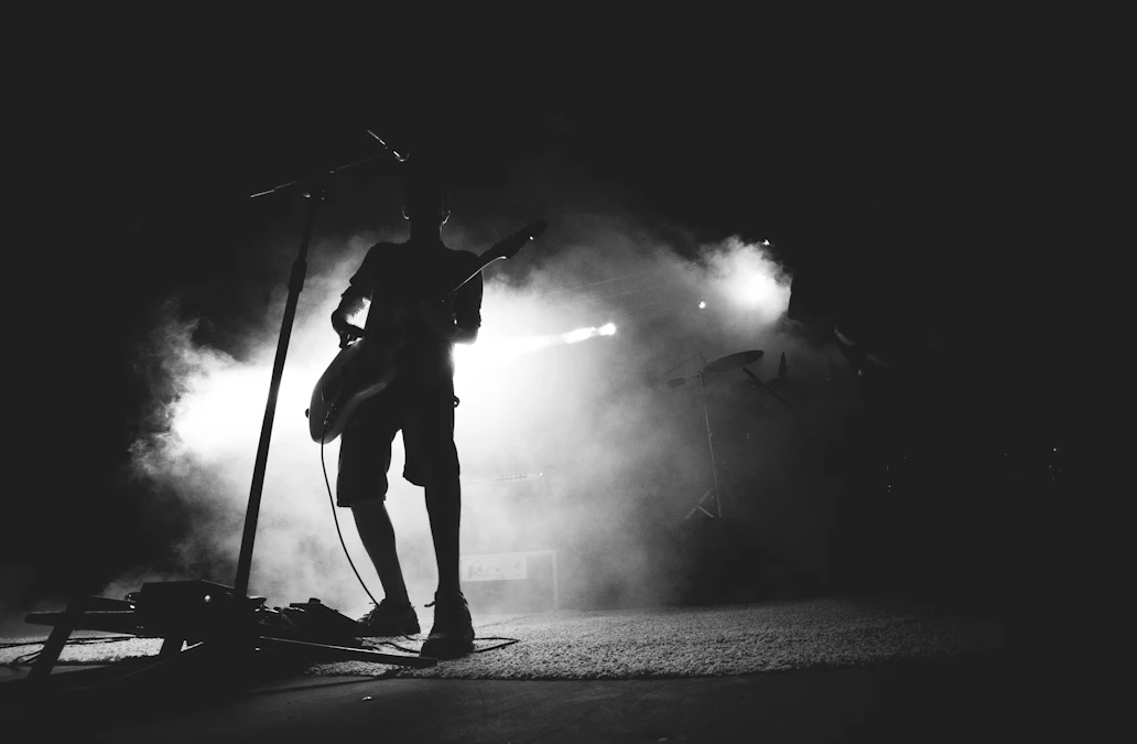 90年代の重低音を背負ったバンドを思わせる、ダークなステージのギタリストのシルエット