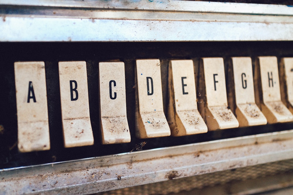 Letter buttons on an old, dirty jukebox.