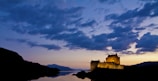 Historic castle illuminated at dusk against a clear sky.