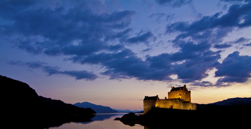Historic castle illuminated at dusk against a clear sky.
