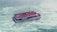 A crowded boat filled with people wearing red rain ponchos is navigating through turbulent waters. The vessel displays a Canadian flag and is surrounded by swirling, frothy water which suggests it might be near a waterfall. The atmosphere is humid and the boat appears to be a tour vessel.