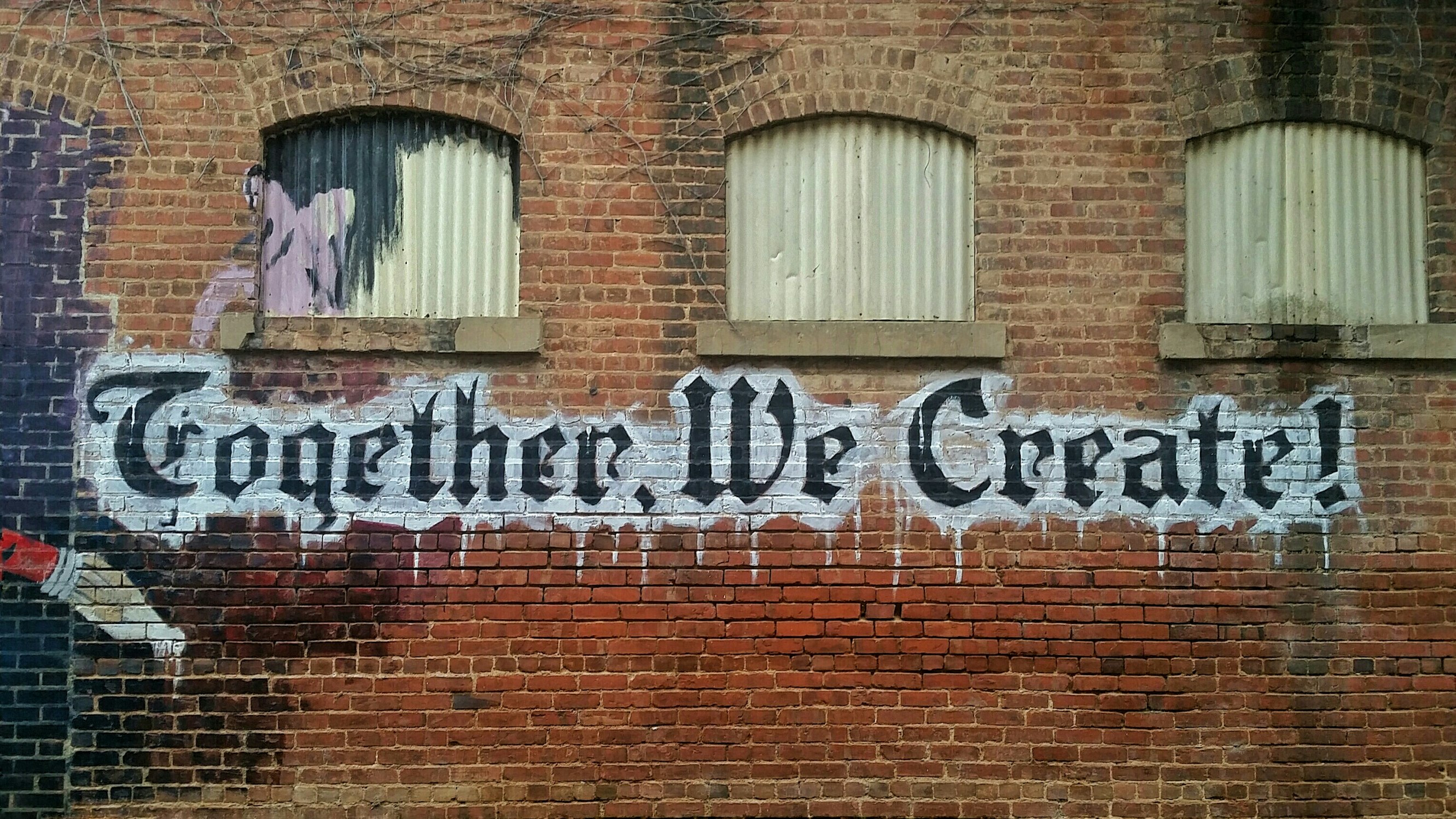 "Together we create" graffiti on wall in black and white paint. Photo by user bamagal
