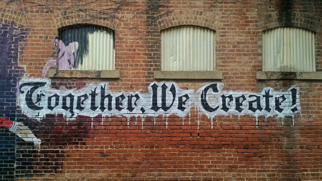 white and black Together We Create graffiti wall decor, “Together, we create!” on brick wall