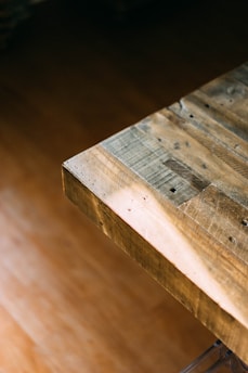 Close-up of hands wiping a wooden table with a microfiber cloth.