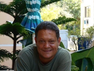 A happy customer enjoying a meal outdoors with a backdrop of lush greenery, smiling warmly.