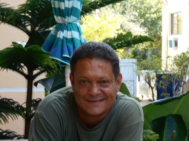 A happy customer enjoying a meal outdoors with a backdrop of lush greenery, smiling warmly.