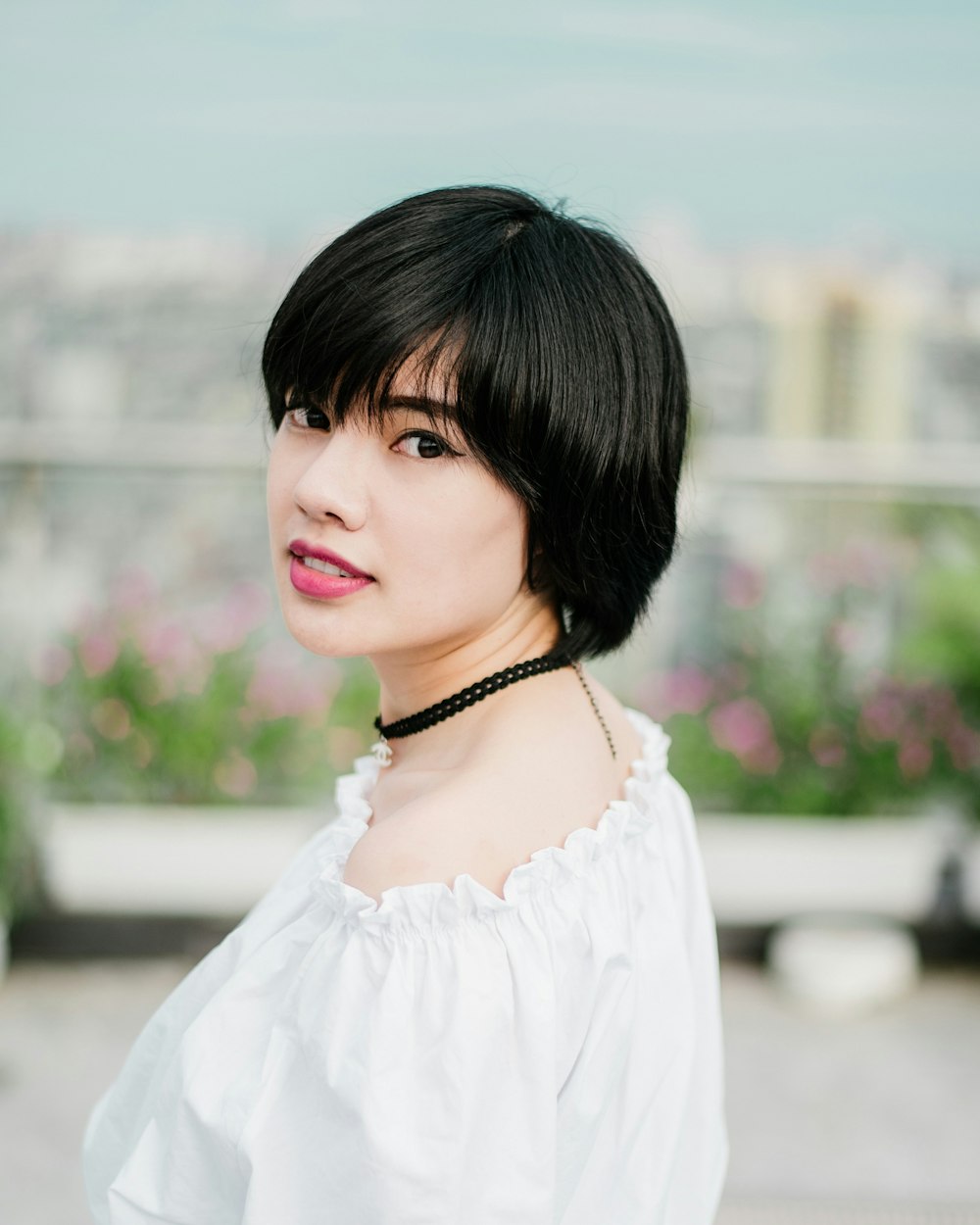 Foto de enfoque selectivo de mujer con top blanco y collar de gargantilla negro