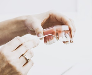 person wearing silver-colored ring while holding denture