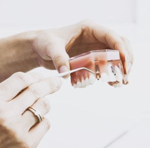 person wearing silver-colored ring while holding denture