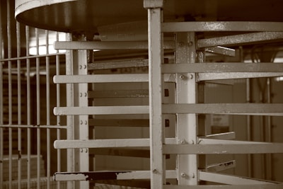 A metallic structure with bars and a circular section, resembling a turnstile, is situated within an industrial or institutional setting.