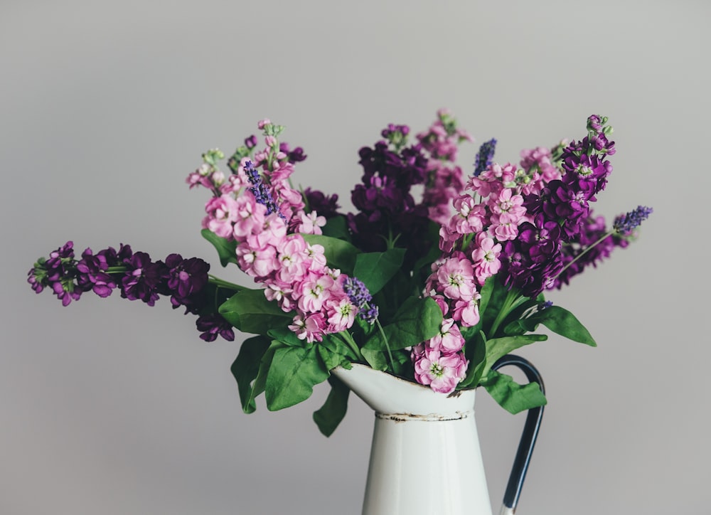 photo of pink and purple petaled flowers with white ceramic vase
